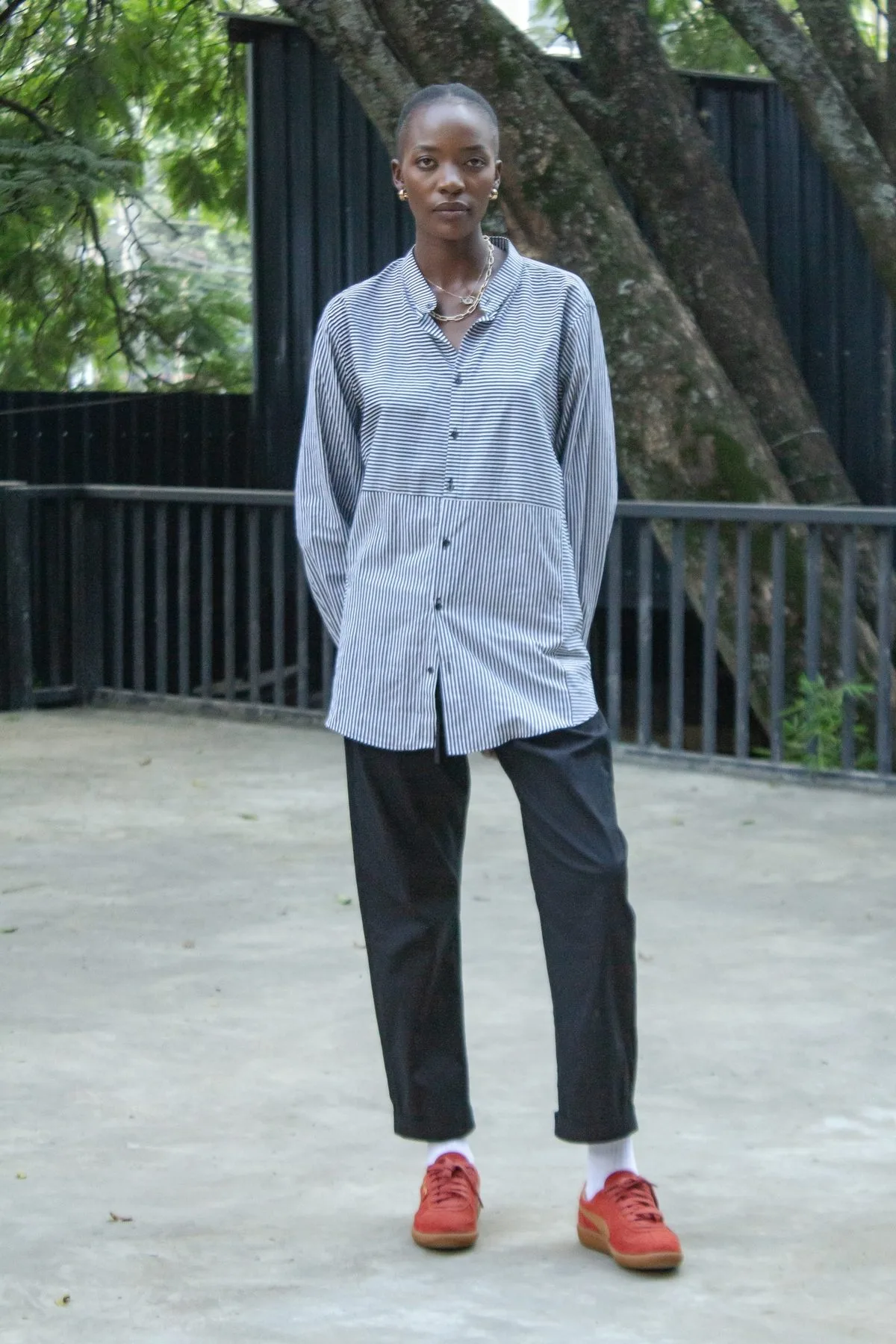 Striped oversized shirt worn with black pleated trousers, full length